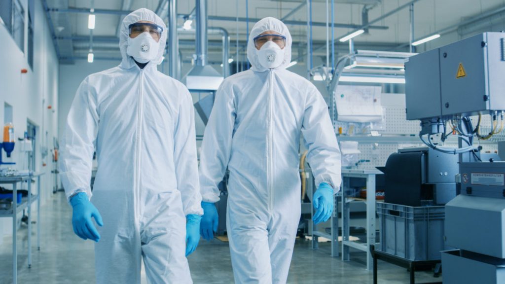 Two Engineers/ Scientists in Hazmat Sterile Suits Walking Through Technologically Advanced Factory/ Laboratory. Clean High-Tech Environment with CNC Machinery.